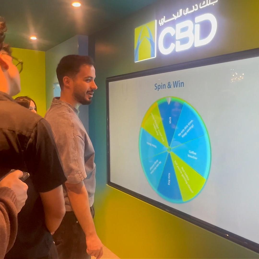 People playing a multi-level interactive financial literacy game at a brand activation event in Dubai, learning how to save and invest money.